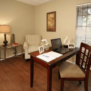 A cozy home office with a desk, chair, and laptop by the window.