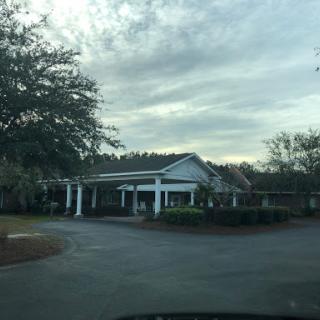 A view of a quaint building surrounded by trees and under a cloudy sky.