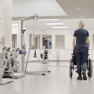 A healthcare professional guiding a wheelchair in a rehabilitation center.