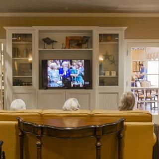 A group of seniors watching television in a cozy living room setting.