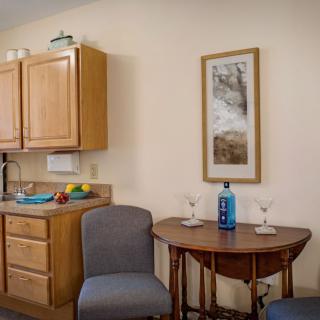 A cozy kitchen corner with a small dining table set for two, featuring wooden cabinets and wall decor.