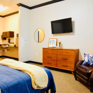 A cozy and modern bedroom interior with a bed, dresser, and wall-mounted TV.