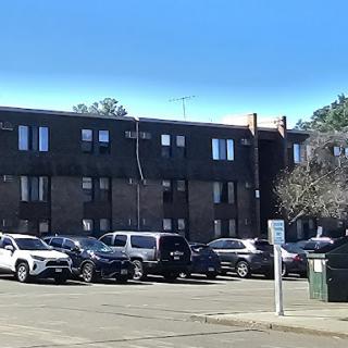 A view of an apartment complex with a parking lot filled with cars.