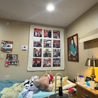 A cozy bedroom featuring a collage of personal photographs on the wall and a neatly made bed with soft bedding.