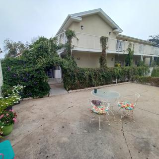 A spacious patio with outdoor furniture in front of a two-story house surrounded by lush greenery.