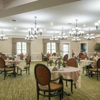 A well-lit, elegant dining room with neatly arranged tables and ornate chandeliers.
