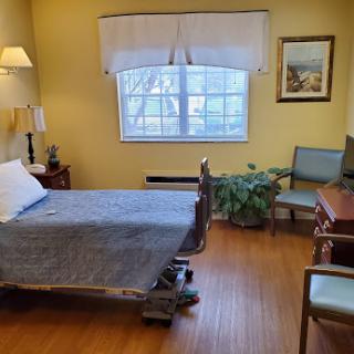 A cozy hospital room featuring a bed, desk, and a window with natural light.
