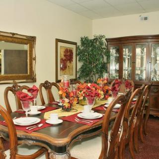 A beautifully set dining room with an elegant table, lush floral arrangement, and traditional decor.