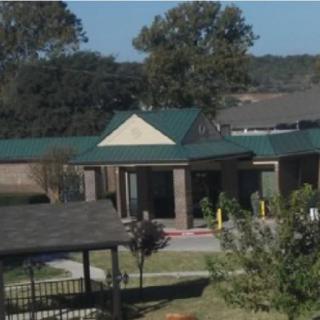 A building with a green roof surrounded by trees and open space.