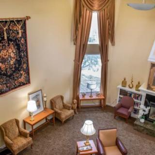 A cozy living room with elegant decor, featuring plush armchairs, a patterned carpet, and a large window with drapes.