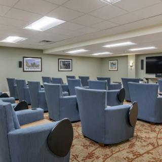 A small theater room with blue chairs and a large screen.