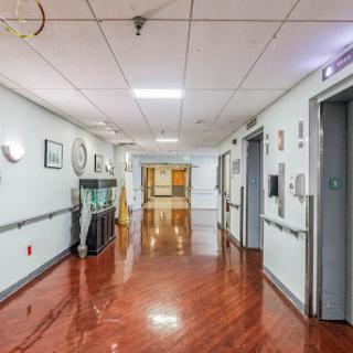 A well-lit hospital corridor featuring polished floors and closed doors.