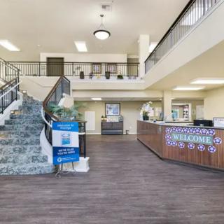 A spacious hotel lobby with a central staircase and a welcoming reception desk.