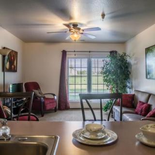 A cozy living room with comfortable seating, a ceiling fan, and large windows.