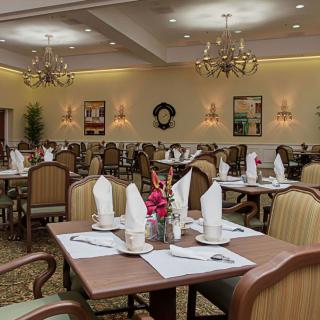 An elegantly arranged dining room with neatly set tables and chandeliers.