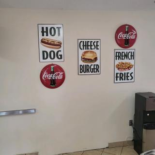 Wall decor featuring signs for hot dogs, cheeseburgers, french fries, and Coca-Cola in a restaurant.