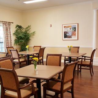 A neatly arranged dining room with multiple tables and chairs, adorned with small plants and wall art.