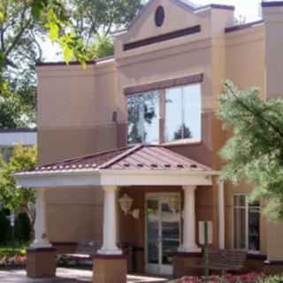 A building entrance with columns and surrounding trees.