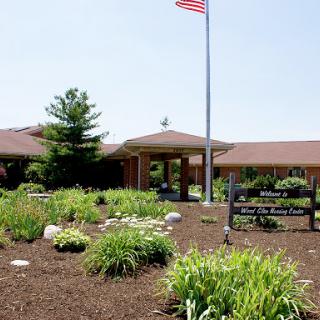 A welcoming entrance with landscaped gardens and an American flag flying.