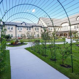 A scenic garden pathway with archways leading to a residential building.