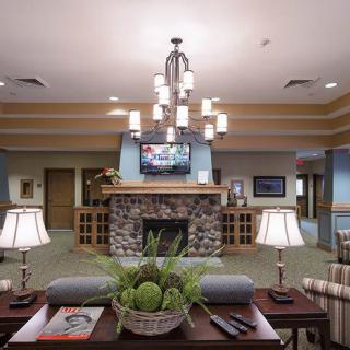A cozy living room with a central stone fireplace, surrounded by comfortable seating and enhanced by a modern chandelier.