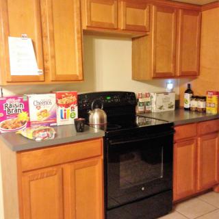 A kitchen with wooden cabinets, a black stove, and various cereal boxes on the countertop.