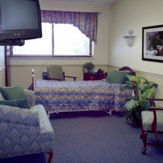 A hospital room with a bed, television, and seating area.