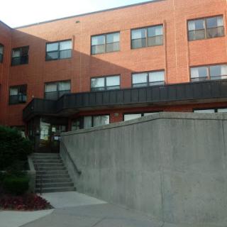 A brick building with multiple windows and a staircase leading to the entrance.