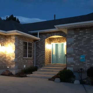 A brick house illuminated by exterior lights at night, showcasing the entrance.