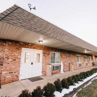 Exterior view of a brick residential building with a pathway and landscaped shrubs.