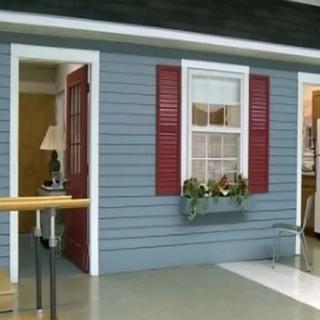Model house interior display with blue siding and red shutters.