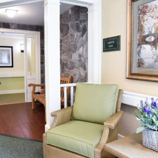A cozy lobby area with a green chair and artwork on the wall.