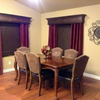 A cozy dining room with a wooden table set and elegant curtains.
