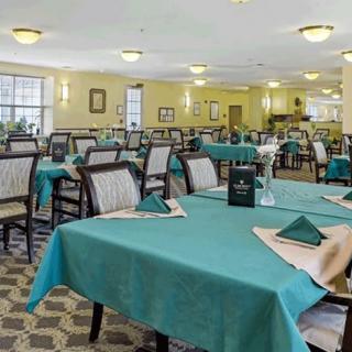 An indoor dining area with neatly arranged tables and chairs, adorned with tablecloths and napkins, creating a welcoming atmosphere.