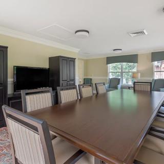 A spacious conference room with a large meeting table, chairs, and a television.
