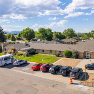 A suburban residential building with parked cars on a sunny day.