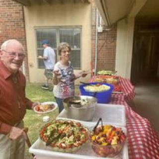 People enjoying an outdoor buffet with various dishes.