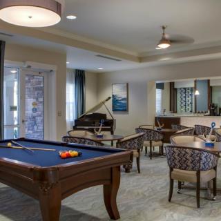 A cozy recreational area featuring a pool table, seating arrangements, and a piano.