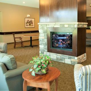 A cozy living room interior featuring a stone fireplace, comfortable seating, and a wooden table with a plant.