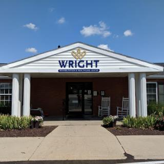 The entrance of the Wright facility, showcasing a welcoming design with rocking chairs and lush landscaping.