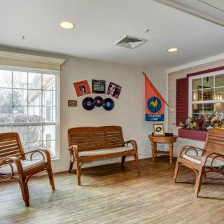 A cozy interior space with wooden chairs, wall decorations, and a large window.