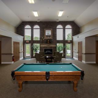 A recreation room featuring a billiard table, a fireplace, and large windows.