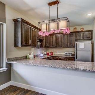 A modern kitchen with granite countertops, wood cabinets, and stainless steel appliances.