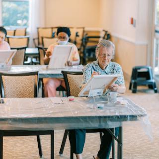 Elderly individuals engaged in a painting class, enjoying a creative and social activity.