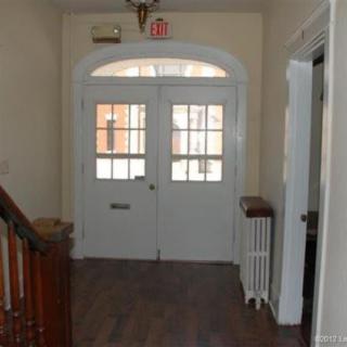 A hallway with double doors, a staircase, and a radiator.