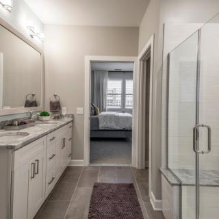 A modern bathroom featuring a sleek vanity, large mirror, and glass-enclosed shower.