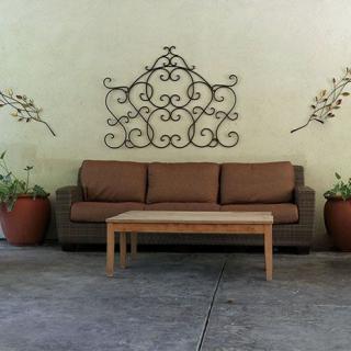 An outdoor seating area featuring a brown sofa, wooden coffee table, decorative wall art, and potted plants.