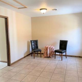 A minimalist room with two chairs and a small round table on a tiled floor.