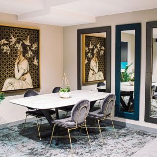 A modern dining room with contemporary artwork, large mirrors, and elegant decor.