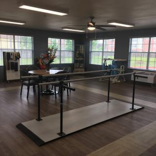 A spacious therapy room featuring a ballet bar and ample natural light.